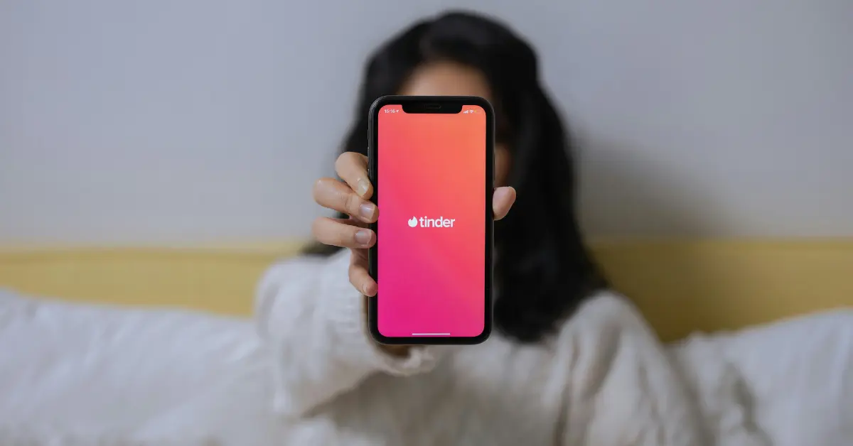 Kobieta przeglądająca aplikację Tinder na smartfonie – poznaj triki, które zwiększą Twoje szanse na dopasowanie